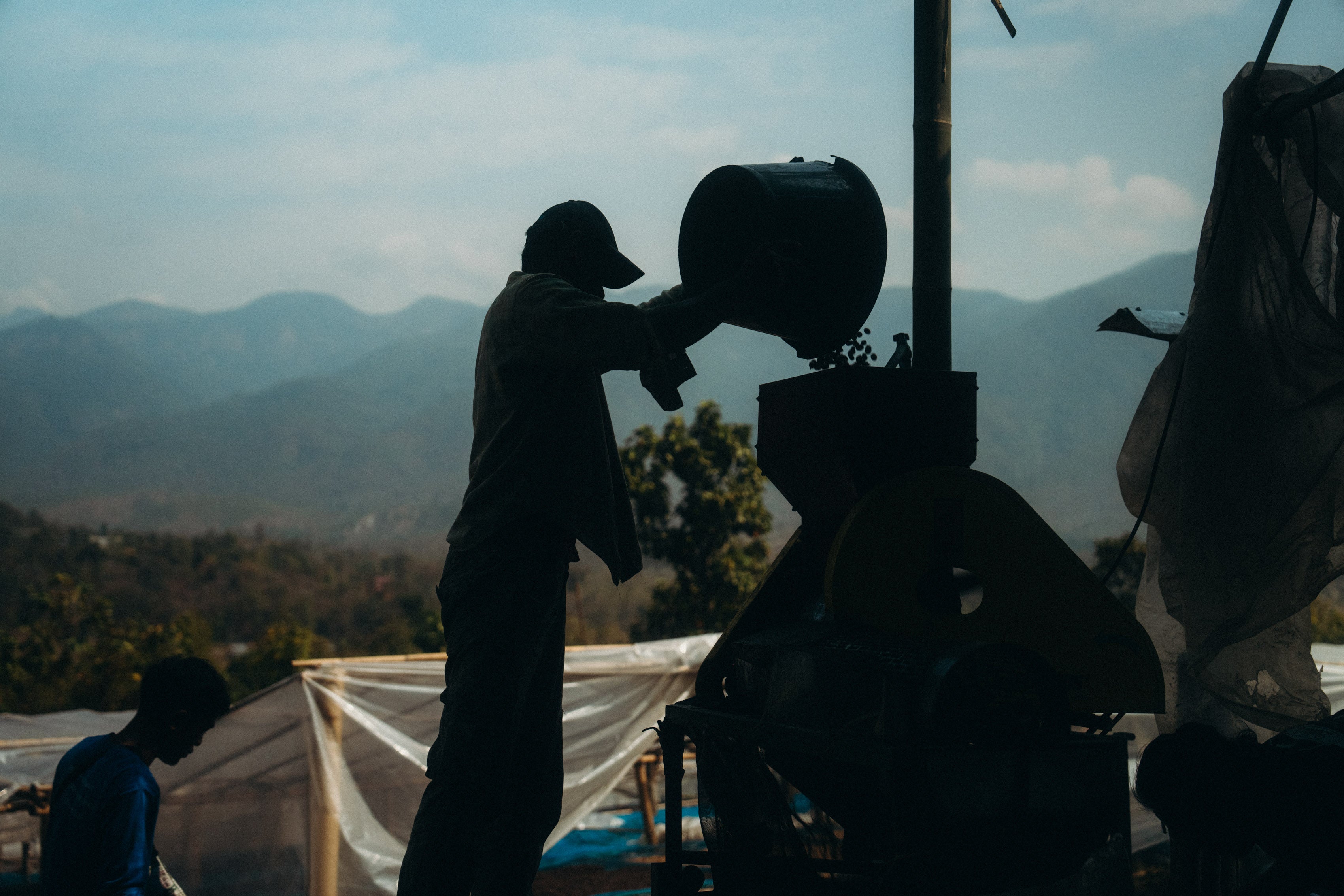 Person operating a large camera on a tripod with mountains in the background.