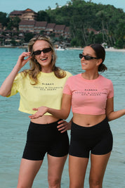 Two women standing by a body of water wearing Bubba's Coffee Crop Tops