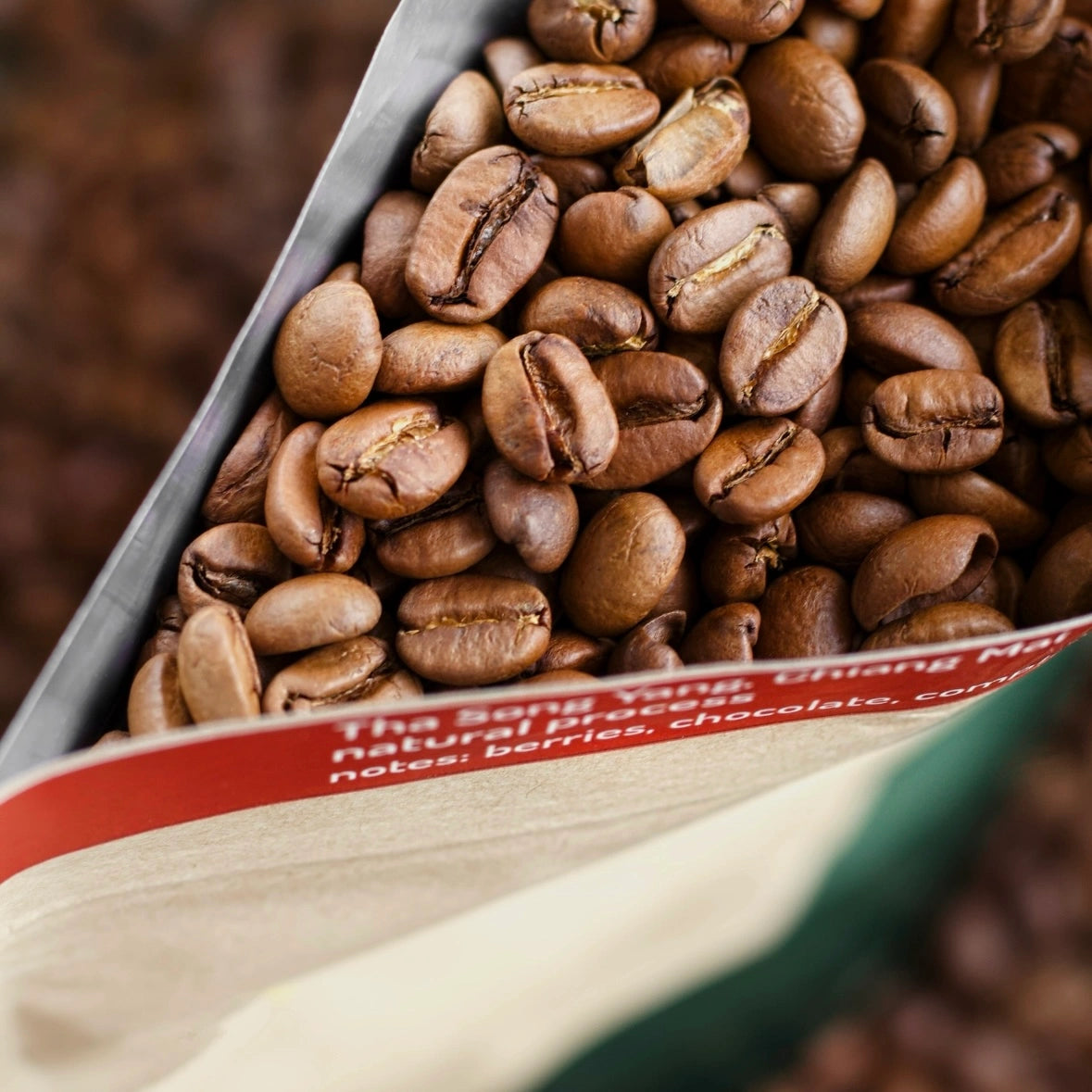 Close-up of coffee beans spilling out of a package with text on it.
