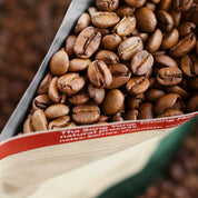 Close-up of coffee beans spilling out of a package with text on it.