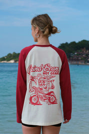 Person wearing a red and white baseball shirt with a graphic design by the water