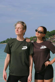 Two people wearing matching t-shirts with a logo on a beach.