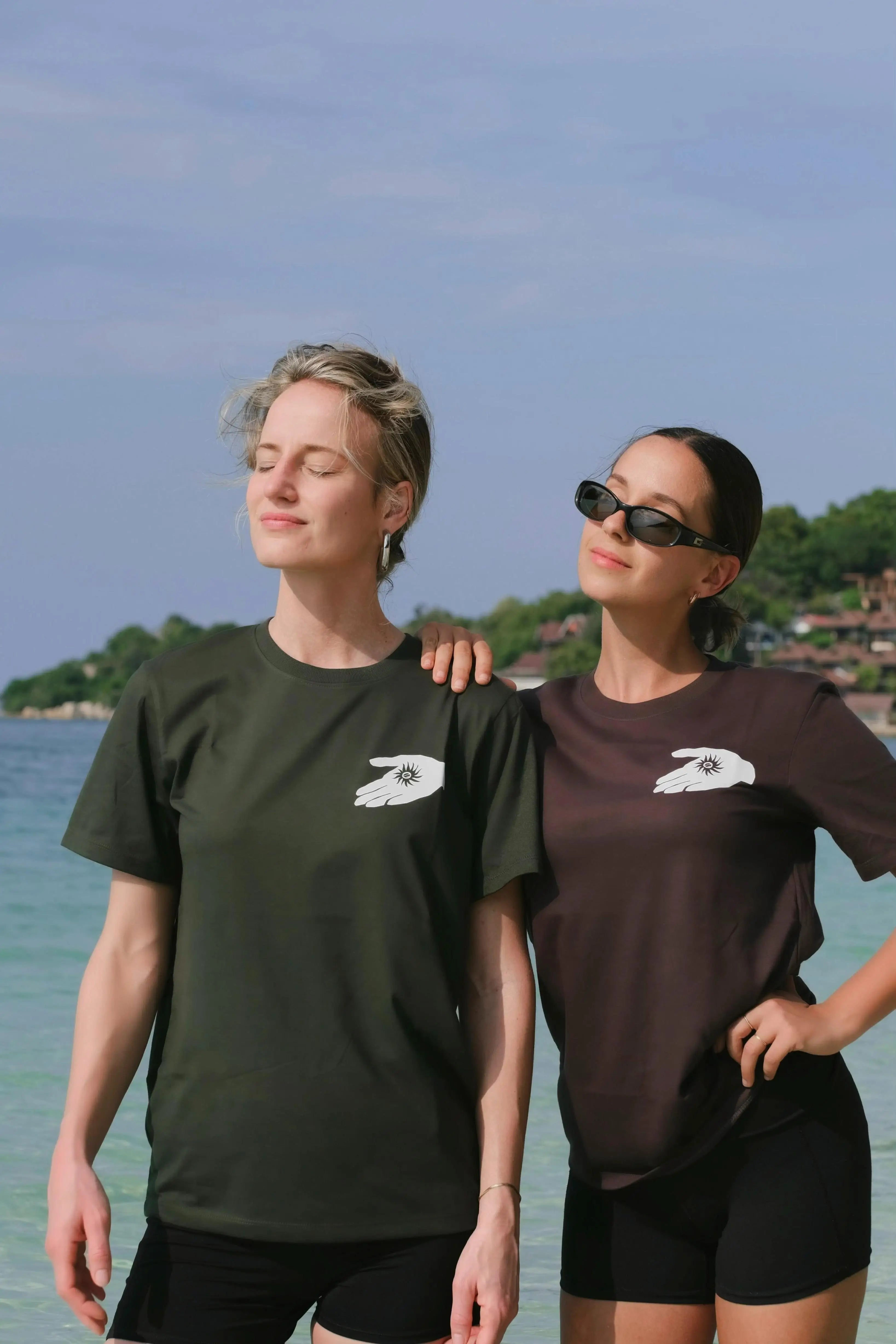 Two people wearing matching t-shirts with a logo on a beach.