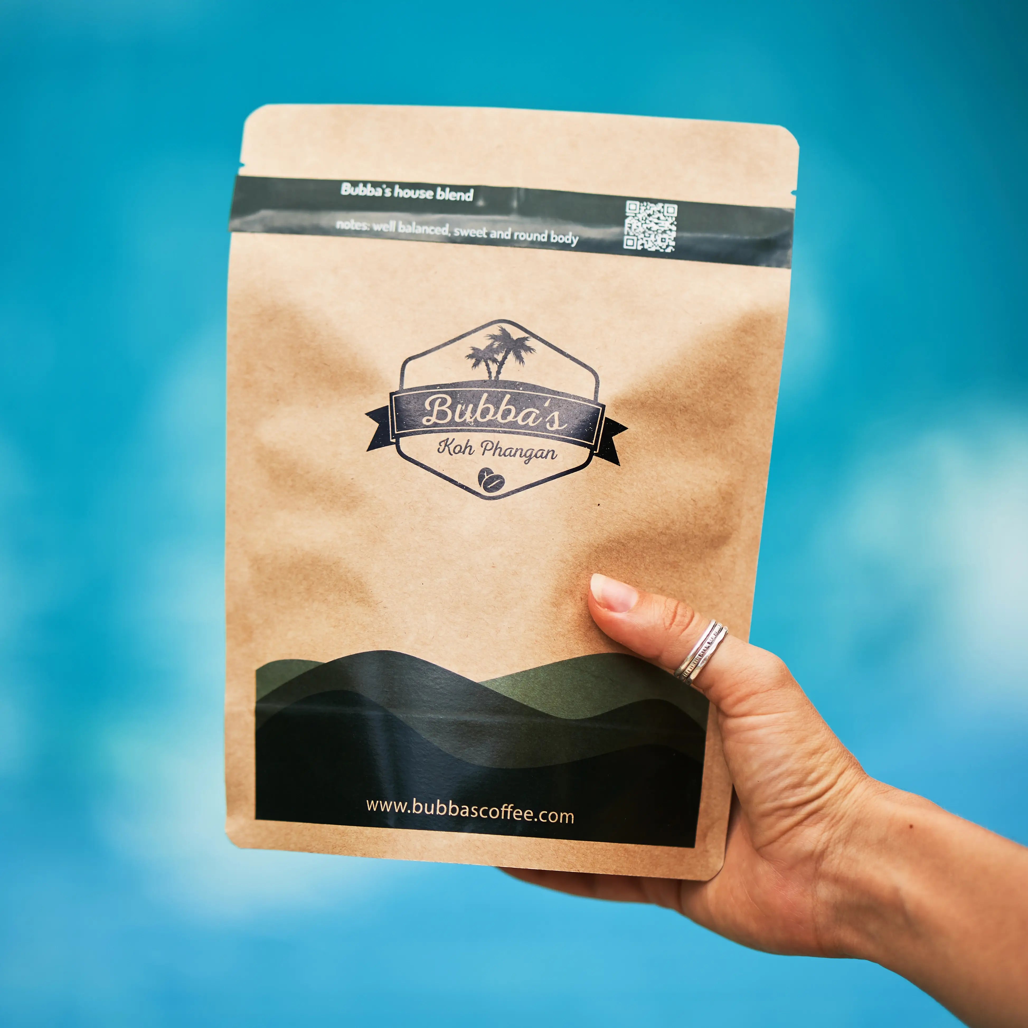 Hand holding a Bubba's Coffee package against a blue background