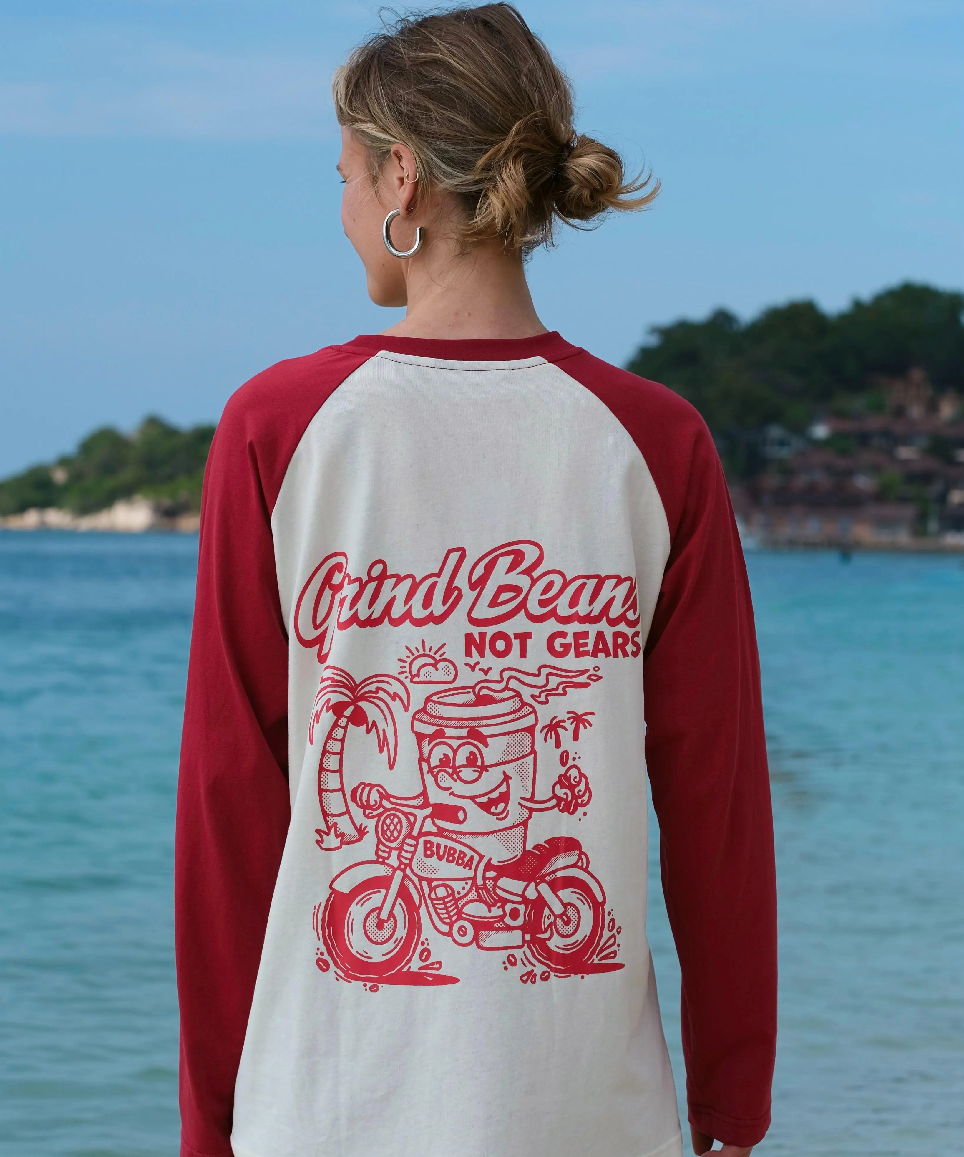 Person wearing a red and white baseball shirt with a graphic design by the water