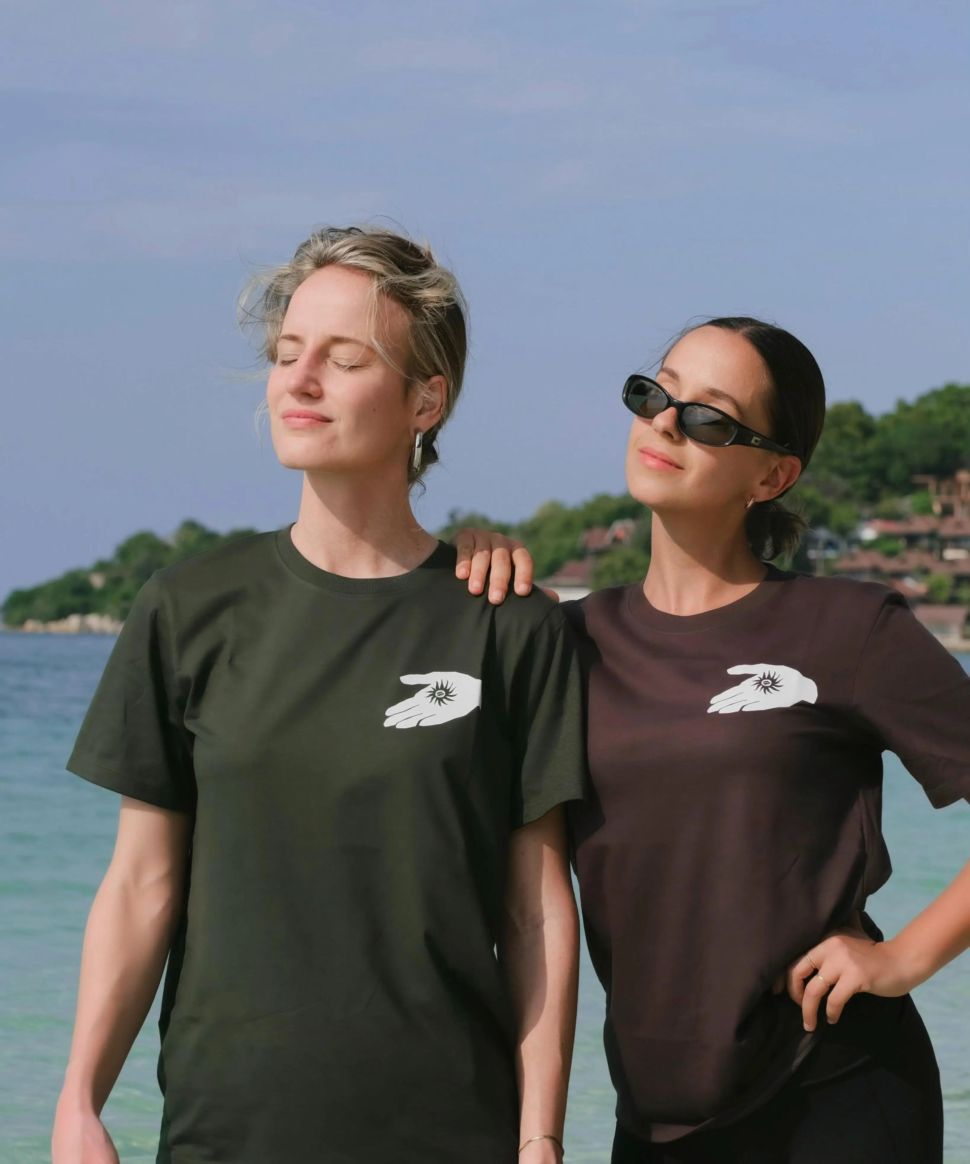 Two people wearing matching t-shirts with a logo on a beach.